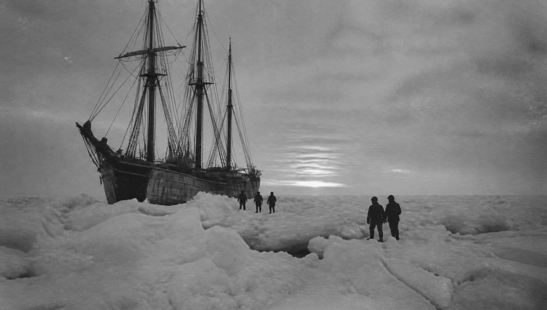 A wooden expedition ship trapped in Antarctic pack ice at dusk
